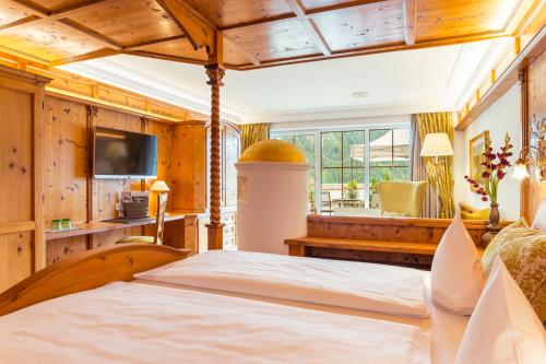 a bedroom with a bed and a television in a room at Via Salina - Hotel am See - Adults Only in Haldensee