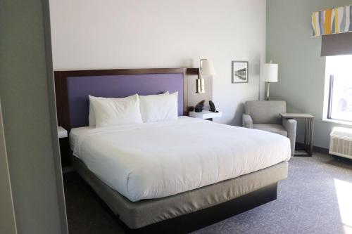 um quarto com uma grande cama branca e uma cadeira em Hampton Inn Mcminnville, Tn em McMinnville