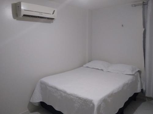 a small bedroom with a white bed with a heater at apartamento em Jacumã in Jacumã