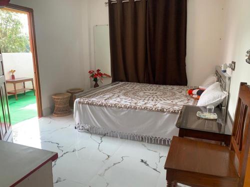 a bedroom with a bed and a table and a window at Sarkar Villa Homestay in Kolkata