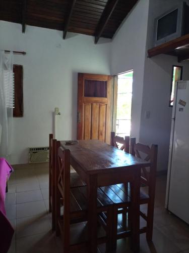 cocina con mesa de madera con sillas y nevera en Alojamiento Lo de Bocha en Gualeguaychú
