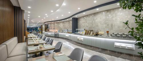 a restaurant with tables and chairs and a counter at Hampton By Hilton Istanbul Airport, Arnavutkoy in Istanbul