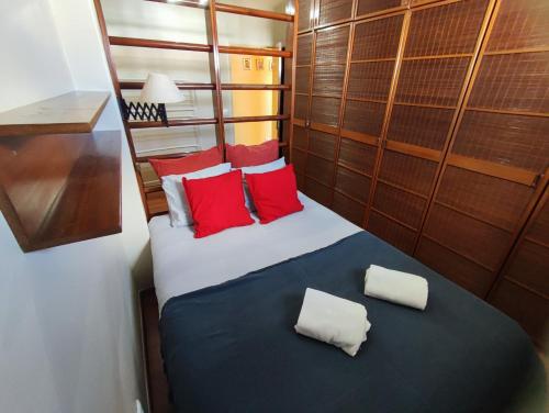 uma cama com almofadas vermelhas e brancas num quarto em Oeiras, 2 bedroom apartment w balcony and barbecue next to Parque dos Poetas em Oeiras