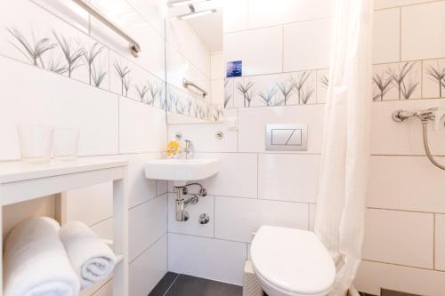 a white bathroom with a toilet and a sink at Gasthof Engel in Obergünzburg