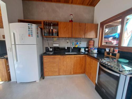 a kitchen with a white refrigerator and wooden cabinets at Camburi Beach House - Casa térrea a 50 m da praia in São Sebastião
