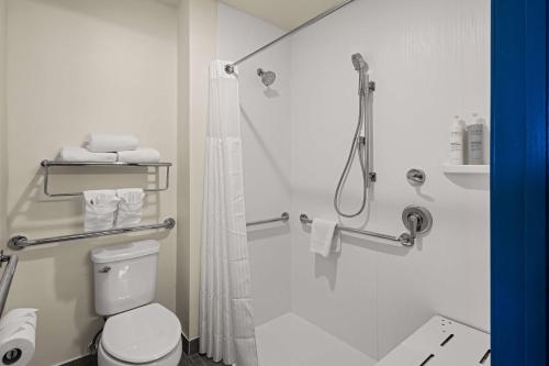 La salle de bains blanche est pourvue d'une douche et de toilettes. dans l'établissement Spark By Hilton Fort Wayne, à Fort Wayne