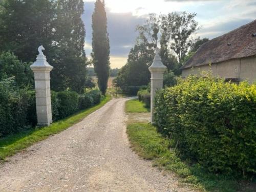 un chemin de terre avec un portail et une maison dans l'établissement Logement Château de Villeneuve, à Saint-Pardoux