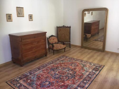une pièce avec une commode, un miroir et un tapis dans l'établissement Logement Château de Villeneuve, à Saint-Pardoux
