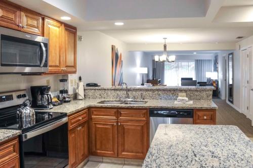 a kitchen with wooden cabinets and granite counter tops at Hilton Vacation Club Polynesian Isles Kissimmee in Kissimmee
