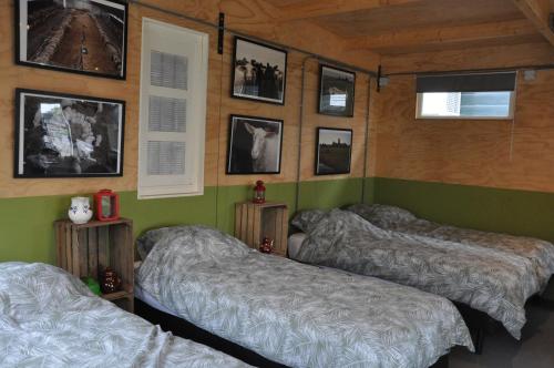two beds in a room with pictures on the wall at Large cottage on sheepfarm in Amsterdam