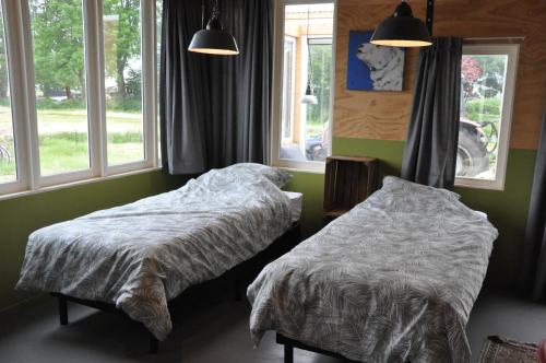 two beds in a bedroom with two windows at Large cottage on sheepfarm in Amsterdam