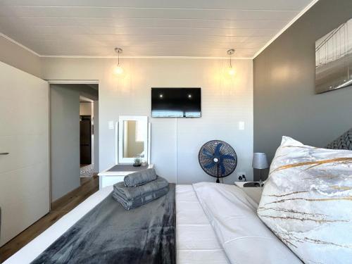 ein Schlafzimmer mit einem großen Bett und einem TV an der Wand in der Unterkunft Coastal Hospitality - De Valle 65 in Mossel Bay