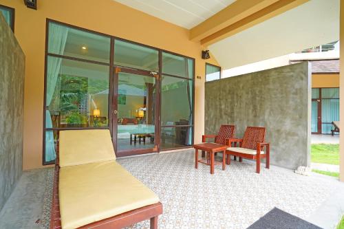 a room with two beds and chairs on a patio at Bundhaya Villas in Ko Lipe