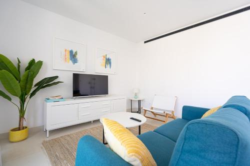 een woonkamer met een blauwe bank en een tv bij El Sol Higueron West Apartment in Fuengirola