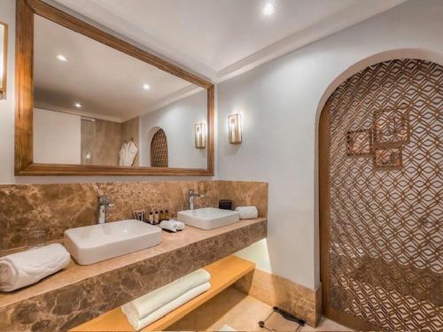Sofitel Agadir Royal Bay Resort في أغادير: حمام به مغسلتين ومرآة كبيرة