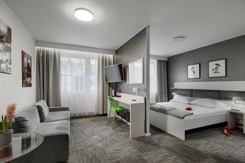 1 dormitorio con cama, escritorio y sofá en Jantar Resort, en Szczecin