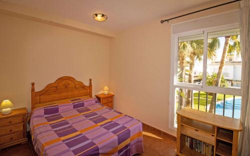 um quarto com uma cama e uma janela em Adosado familiar con piscina - Palm Beach 40 ALBERT VILLAS em Alcossebre