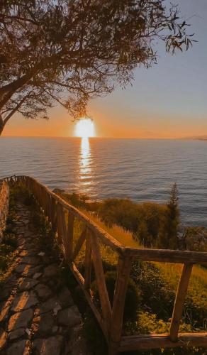 a sunset over the water with a wooden fence at Casa Erika in Bova Marina