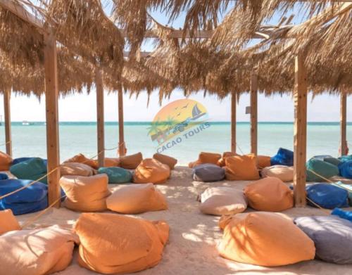 a group of pillows on a beach with an umbrella at Orange Bay in Hurghada