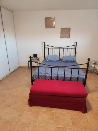 - une chambre avec un lit doté d'un pouf rouge dans l'établissement Charmante maison de village pour 10, à 15 min de la mer - Idéal familles et amis, à Montblanc