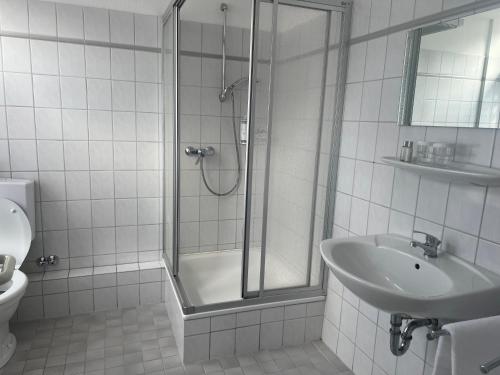 a white bathroom with a shower and a sink at Bierstadt-Hotel in Einbeck