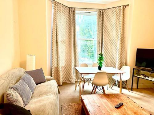 a living room with a couch and a table and a window at Peaceful park side apartment in Hastings