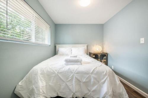 a bedroom with a bed with white sheets and a window at Flagstone Hall! Family Home w Scenic Views in Colorado Springs