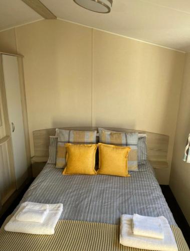1 dormitorio con 1 cama con almohadas amarillas en Family Caravan, Seton sands, Haven holiday village, en Port Seton