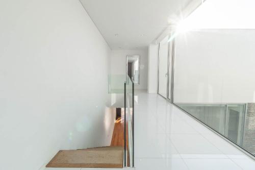 um corredor com paredes brancas e uma escada de vidro em Akivillas Sintra Star em Sintra