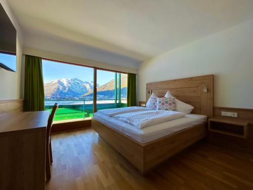 a bedroom with a bed and a large window at Appartements Achensee in Maurach