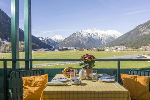a table with a yellow table cloth and a view of mountains at Appartements Achensee in Maurach