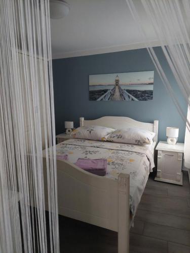a bedroom with a white bed and blue walls at Studio Nikola in Baška