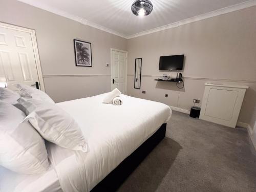 a bedroom with a large white bed and a tv at The Exchange Hotel in Brigg
