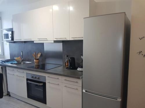 a kitchen with white cabinets and a refrigerator at Shiny Compiègne Logement Entier in Compiègne