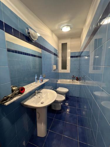 - une salle de bains carrelée de bleu avec 2 toilettes et un lavabo dans l'établissement Daeiouz II, à Milan