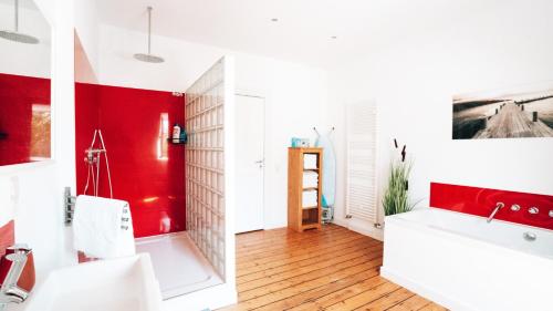 ein Bad mit roten und weißen Wänden und einem roten Waschbecken in der Unterkunft 4-Schlafzimmer-Terrassensuite Oasis - WORKSPACE EM-APARTMENTS DEUTSCHLAND in Bielefeld