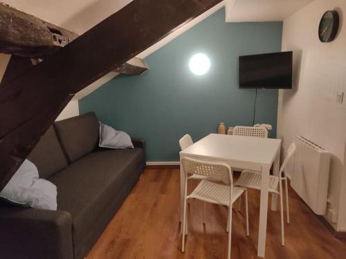 a living room with a couch and a table and chairs at Studio Rémois - WIFI/Netflix in Reims