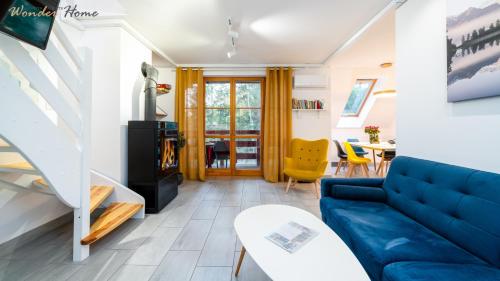 a living room with a blue couch and a table at Wonder Home - Domki górskie z kominkami, bezpłatnym parkingiem i placem zabaw na terenie kompleksu in Karpacz