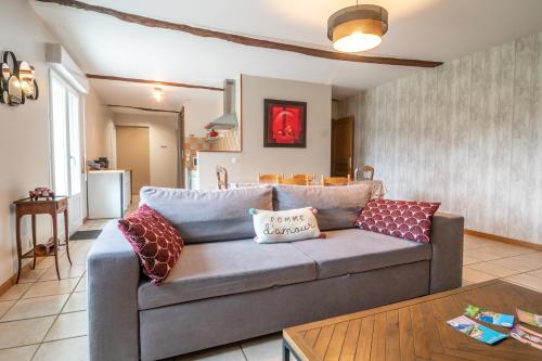 un soggiorno con divano grigio e cuscini di L'Îlot Pomme Cottage a Campigny