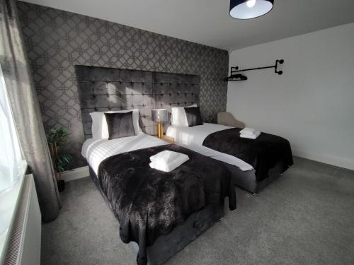 a hotel room with two beds with black blankets at Sirius House - sleeps 7, driveway, garden in Crewe