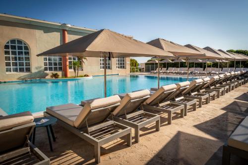 a row of chairs and umbrellas next to a swimming pool at C&ocirc;t&eacute; Thalasso H&ocirc;tel & Spa Marin in Banyuls-sur-Mer