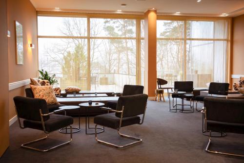 una sala de espera con sillas, mesas y ventanas en Silva Hotel Spa-Balmoral, en Spa