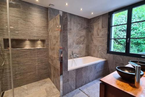 ein Badezimmer mit einer Badewanne und einem Waschbecken in der Unterkunft Villa 35 minutes Paris in Saint-Prix