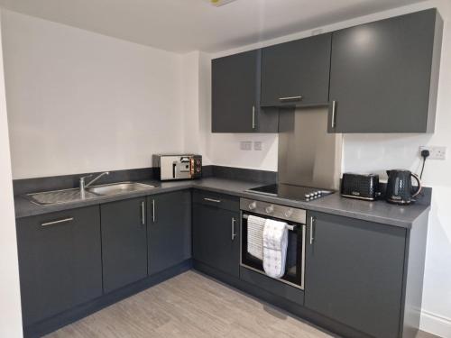 a kitchen with black cabinets and a sink at Wakefield Getaway - Cosy Apt with Free Parking in Wakefield