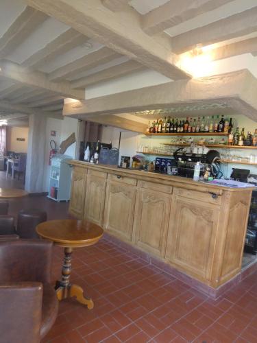 a bar with wooden cabinets and a table and chairs at Logis Hôtel Restaurant Auberge Saint Martin in Surville