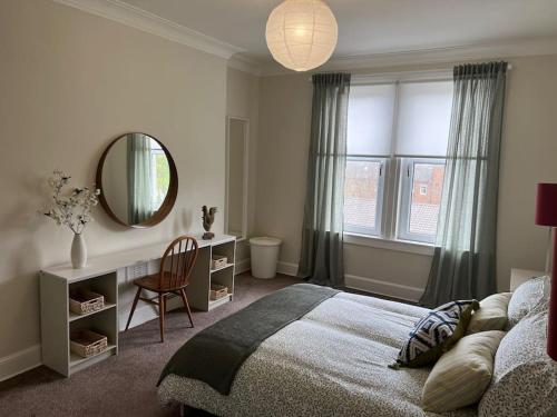 um quarto com uma cama, um espelho e uma cadeira em Stylish & Central Flat in Edinburgh. Free Parking em Edimburgo