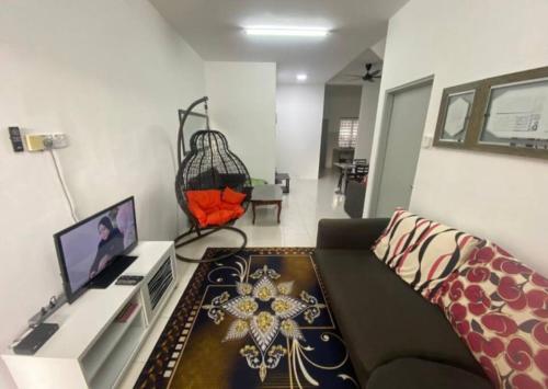 een woonkamer met een bank en een televisie bij Azman Homestay in Batu Gajah