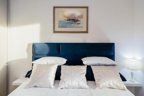 a bed with a blue headboard and white pillows at Little Paradise in Split