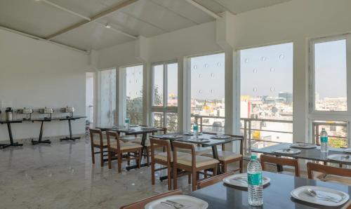 a dining room with tables and chairs and windows at Treebo Global Stay, Jayanagar in Bengaluru
