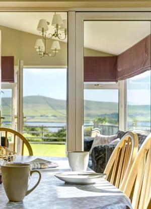 a dining room with a table and chairs with a view at 18 Ard na Mara in Dingle